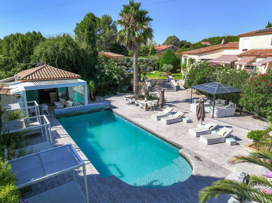 Grande piscine extérieure de Casa Dina à Sommières avec transats, salon lounge et jardin méditerranéen