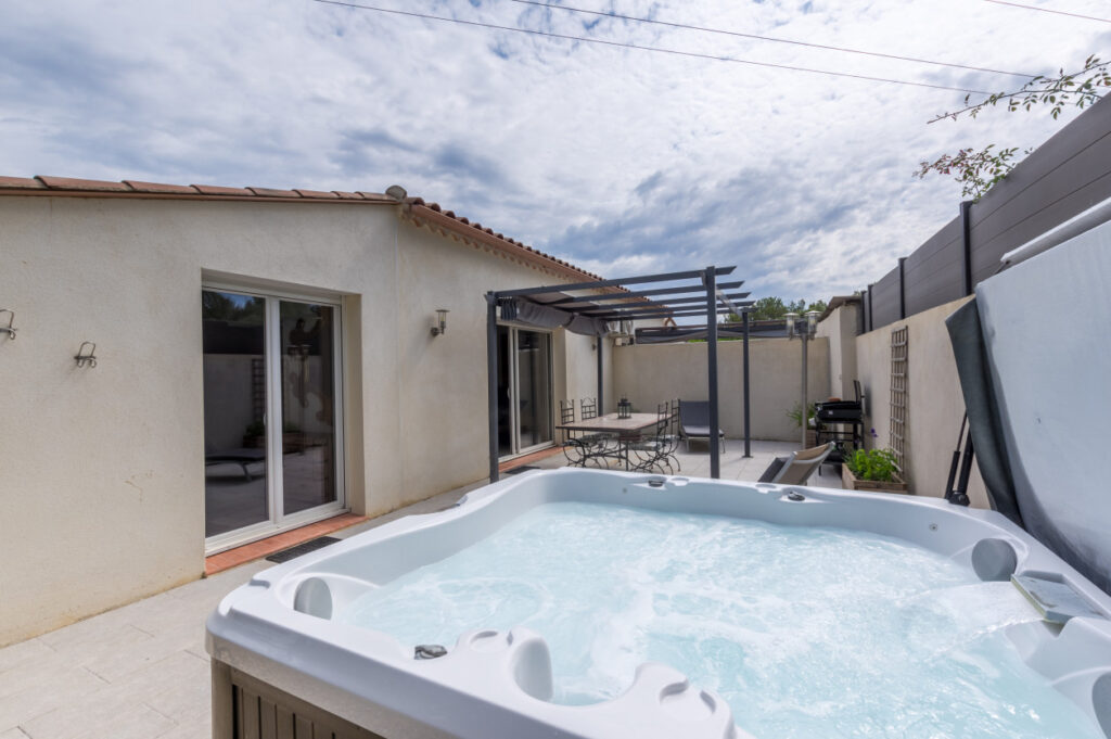 Terrasse de Casa Dina Sommières avec jacuzzi privatif, pergola et espace repas extérieur