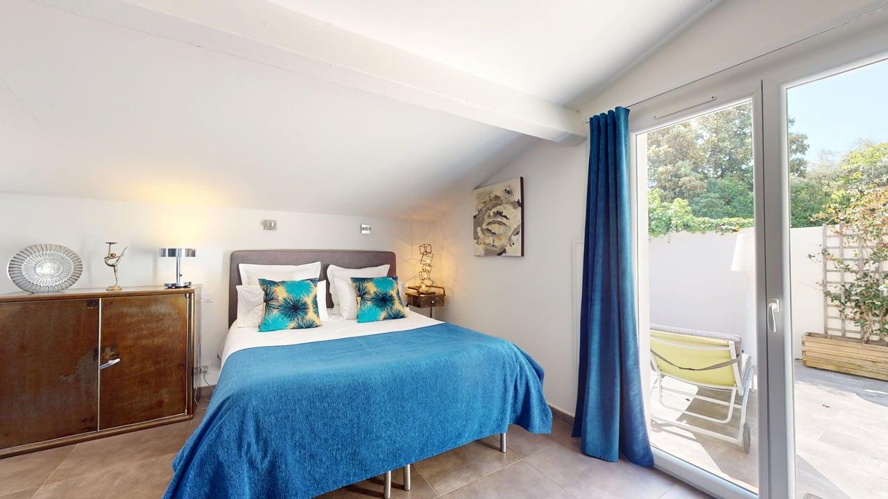 Chambre Villa CUBIC lit bleu coussins tropicaux terrasse ensoleillée
